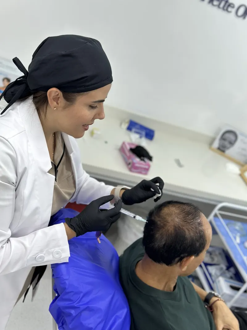 La Dra. Arlette Ortega, médica tricóloga en Bucaramanga, revisando el cuero cabelludo de un paciente